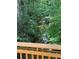 A tranquil creek surrounded by dense greenery, viewed from a bridge with wooden railings at 4774 Olde Village Ln, Atlanta, GA 30338