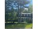 Charming two-story home with a landscaped lawn, blue door and mature trees providing ample shade at 4774 Olde Village Ln, Atlanta, GA 30338