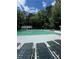 A wide swimming pool with lounge chairs, umbrellas and a white pool house surrounded by trees and clear blue skies at 4774 Olde Village Ln, Atlanta, GA 30338