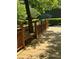 Wood deck near tennis courts with bench seating shaded by trees, inviting relaxation and community interaction at 4774 Olde Village Ln, Atlanta, GA 30338