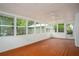 Bright sunroom with many windows, ceiling fan, painted wood flooring, and view of backyard landscaping at 599 Honey Creek Rd, Conyers, GA 30094