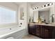 Bright bathroom with tub, dual vanity, and decorative window at 6235 Crescent Landing Dr, Cumming, GA 30028