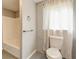 Bathroom with white toilet, shower, and window with white curtains at , Mableton, GA 30126