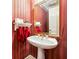 Charming powder room featuring pedestal sink, decorative mirror, and vibrant striped wallpaper at 1820 Habersham Gate Dr, Cumming, GA 30041