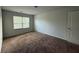 Simple bedroom with neutral carpeting, a bright window, and a standard door at 545 Tulip Ln, Mcdonough, GA 30252