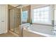 Bright bathroom featuring a large bathtub, glass shower, and decorative window at 6805 Bransford Dr, Cumming, GA 30040