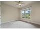 Empty bedroom with ceiling fan, neutral walls, and large window overlooking yard at 6805 Bransford Dr, Cumming, GA 30040