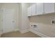 Bright laundry room with tile floor, white cabinets, and a door leading to other parts of the house at 6805 Bransford Dr, Cumming, GA 30040