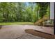 Expansive backyard with mature trees, a patio, and a wooden staircase at 9438 Cedar Creek Pl, Douglasville, GA 30135