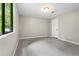 Basement bedroom with a large window showcasing backyard greenery, neutral walls, and plush carpeting at 9438 Cedar Creek Pl, Douglasville, GA 30135