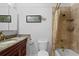 Well-lit bathroom with granite counters, traditional cherry-stained cabinets and a shower with built-in shelving at 1421 Peachtree Ne St # 214, Atlanta, GA 30309