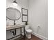 Modern half bathroom features a concrete sink, round mirror, and decorative wall art at 110 3Rd St, Fayetteville, GA 30214