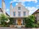 Charming three-story home with a symmetrical facade, covered porch with lush greenery, and striking architectural details at 110 3Rd St, Fayetteville, GA 30214