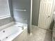 Bright bathroom featuring a soaking tub with a white marble surround, and a door leading to other rooms at 1255 Summit Point Ln, Snellville, GA 30078