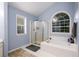 Well-lit bathroom featuring a shower, tub, and large windows at 2759 Beddington Way, Suwanee, GA 30024