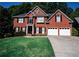 Beautiful two-story brick home boasts an attached two car garage, verdant lawn, and meticulously manicured shrubbery at 308 Forkwood Trl, Woodstock, GA 30189