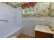 Compact bathroom with a shower-tub combo, white tiling, and a floral wallpaper accent at 100 Biscayne Nw Dr # D7, Atlanta, GA 30309