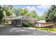 Exterior showcasing a brick house with an attached carport, sunroom, and wooden deck with lush greenery at 2044 Wilandrew Dr, Decatur, GA 30033