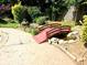 Charming backyard bridge over a small creek leading to a gate and surrounded by lush greenery and decorative rocks at 1244 Hickory Wood Ne Dr, Woodstock, GA 30188