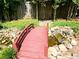 Charming backyard bridge over a small creek leading to a gate and surrounded by lush greenery and decorative rocks at 1244 Hickory Wood Ne Dr, Woodstock, GA 30188