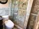 Bathroom featuring stone tile, dark vanity, luxury toilet and glass door shower at 1244 Hickory Wood Ne Dr, Woodstock, GA 30188