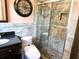 Bathroom featuring stone tile, dark vanity and glass door shower at 1244 Hickory Wood Ne Dr, Woodstock, GA 30188