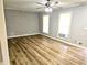 Living room featuring wood flooring, two windows, ceiling fan and modern fixtures at 1244 Hickory Wood Ne Dr, Woodstock, GA 30188