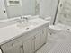 Bright bathroom featuring sleek vanity, toilet, black and white floor tiles, and a glass-enclosed shower at 3045 Revere Cir, Snellville, GA 30039