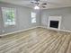 Spacious living room with two windows, a fireplace with white mantel, and light wood grain vinyl plank flooring at 3045 Revere Cir, Snellville, GA 30039