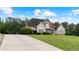 Charming two-story home with a stone and stucco facade, arched entryway, balcony, and lush landscaping at 11440 Azalea Trl, Hampton, GA 30228