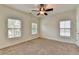 Spacious bedroom featuring carpet floors, a ceiling fan, and three windows providing ample natural light at 375 Causeway Ct, Suwanee, GA 30024