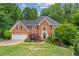 Charming two-story brick home with a well-manicured lawn, lush landscaping, and a two-car garage at 420 Windswept Ct, Roswell, GA 30075