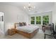 Light bedroom featuring a large bed, modern lighting, and a scenic window view at 11255 Wittenridge Dr, Alpharetta, GA 30022