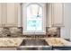 Close up of a gourmet kitchen sink with a granite counter and tile backsplash at 2370 Bradwardine Ct, Cumming, GA 30041