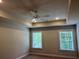 Well-lit bedroom features a tray ceiling with recessed lighting, two windows, and neutral carpet and walls at 2409 Malster Ln, Lawrenceville, GA 30043