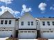 Charming townhome showcasing white siding, brick accents, and a well-maintained two-car garage with lovely landscaping at 2409 Malster Ln, Lawrenceville, GA 30043