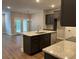 Open-concept kitchen featuring an island with a sink, granite countertops, stainless steel appliances, and dark cabinets at 2409 Malster Ln, Lawrenceville, GA 30043