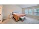 Bright bedroom with neutral walls and carpet features a bed, two furry stools, and three large windows at 1262 Brookstone Cir, Conyers, GA 30012