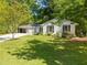 Well-maintained single-story home with white brick, a manicured lawn, and mature trees providing shade at 3176 Gablewood Ct, Decatur, GA 30033