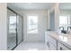 Bathroom with a frameless glass shower, marble floors, black hardware, and a white vanity under a window at 405 Carrera Ln, Acworth, GA 30102