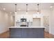 Open kitchen with a gray island, white cabinets, modern appliances, and stylish pendant lighting at 405 Carrera Ln, Acworth, GA 30102