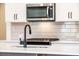 Close-up of a gas cooktop and stainless steel microwave with white cabinets and a modern faucet at 405 Carrera Ln, Acworth, GA 30102