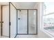 Modern shower with frameless glass door, marble tile surround, and black fixtures, complemented by a large window at 405 Carrera Ln, Acworth, GA 30102