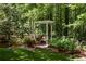 Green grass backyard with a pergola swing and bordered by trees and greenery at 9179 Selborne Ln, Chattahoochee Hills, GA 30268
