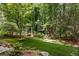 Landscaped backyard with green lawn, rock decorations and surrounded by trees at 9179 Selborne Ln, Chattahoochee Hills, GA 30268