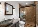 Bathroom featuring stone vessel sink, tiled walk-in shower with glass door, and warm lighting at 9179 Selborne Ln, Chattahoochee Hills, GA 30268