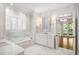 A luxurious bathroom features marble accents, a soaking tub, and a view to the outside deck at 9179 Selborne Ln, Chattahoochee Hills, GA 30268