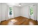 Bright bedroom featuring hardwood floors, two windows with white curtains, and a ceiling fan at 9179 Selborne Ln, Chattahoochee Hills, GA 30268