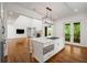 White kitchen with island gas range and open-concept design to the living room and fireplace; natural light at 9179 Selborne Ln, Chattahoochee Hills, GA 30268