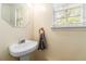 Small bathroom with pedestal sink, mirror, towel rack, and window at 4065 Waters End Ln, Snellville, GA 30039